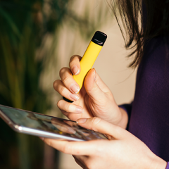 young woman holding vape and smartphone
