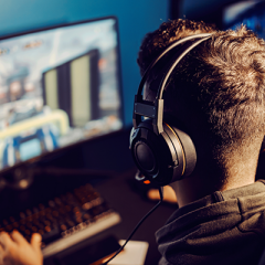 Young man video gaming on computer wearing heaphones
