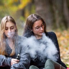 Two teens vaping in a park