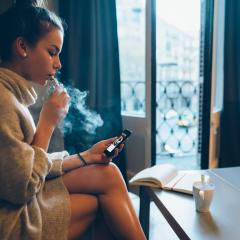 young woman on phone vaping 